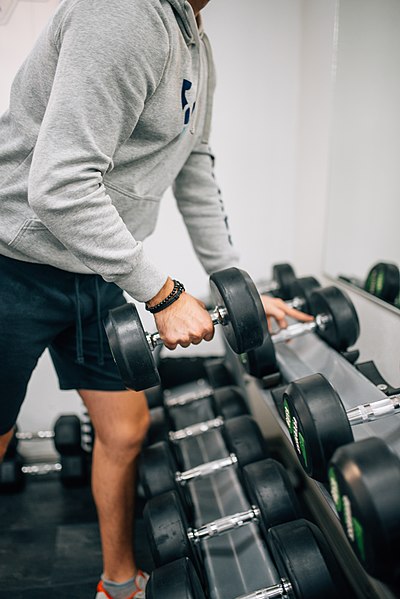 Attractive_man_lifting_dumbbell_weight_for_exercise_in_fitness_gym.jpg